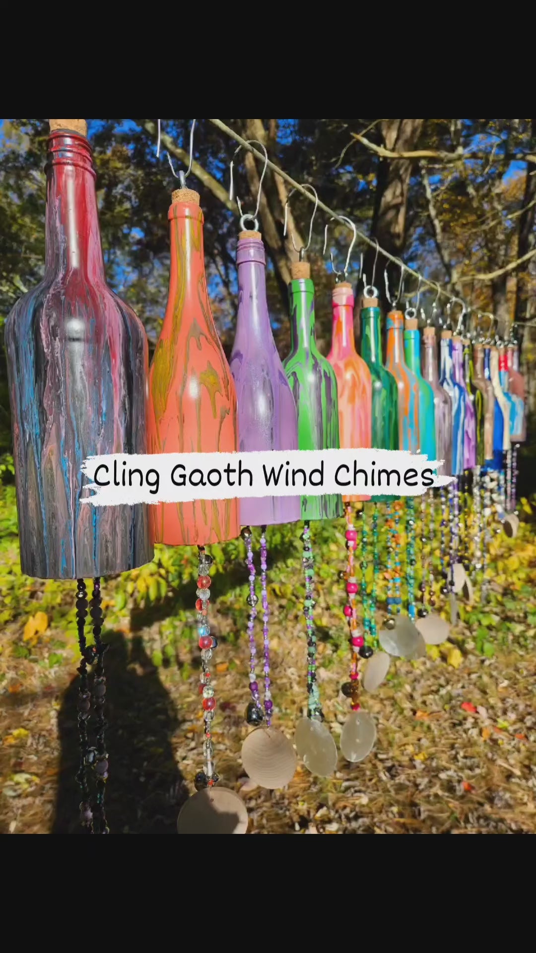 Load video: Wind Chimes Hung on a Line Making Mixed Bell Sounds In Front of Large Trees