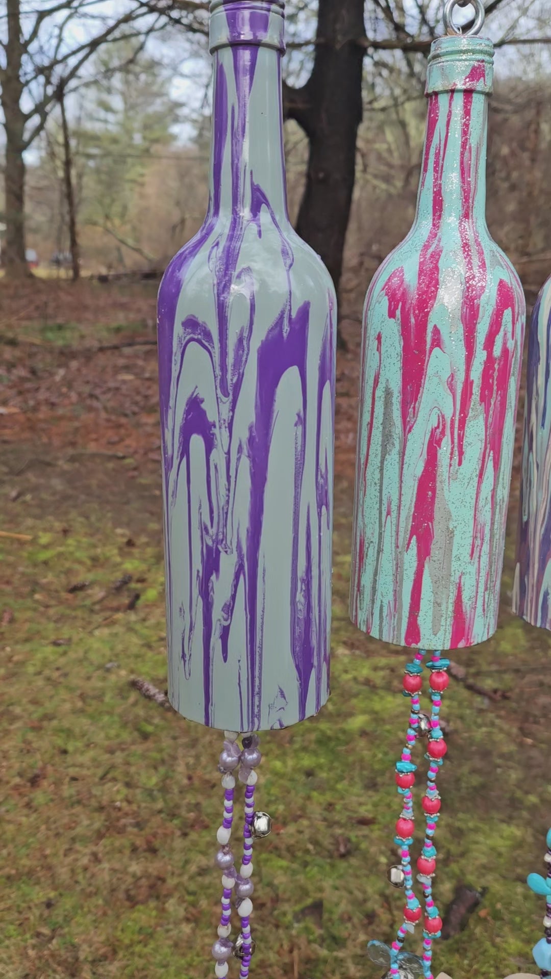 Load video: Wind Chimes Hung on a Line Making Mixed Bell Sounds In Front of Large Trees